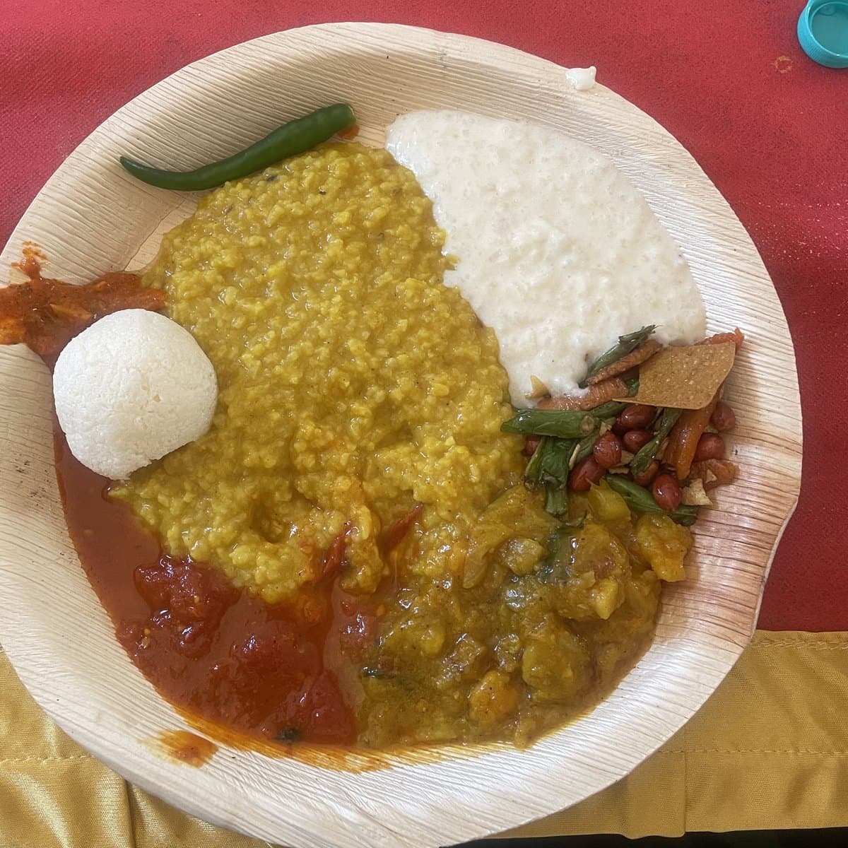 A plate of bhog on a leaf plate: khichdi, rice, curries and a green chilli