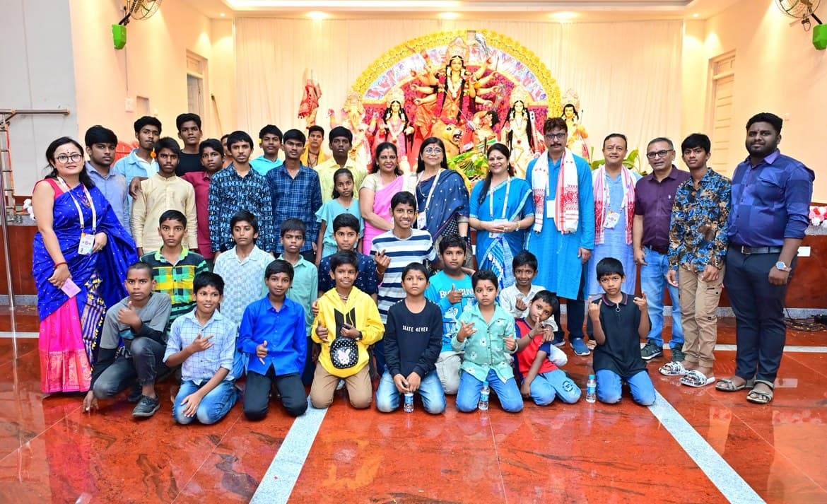 Children who were guests at Durgapatra Abhiyan with AAB members and volunteers, standing in front of the Durga idol at the Puja